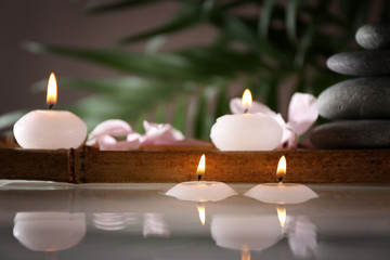 Fototapeta na wymiar Spa still life with candles in water on natural blurred background