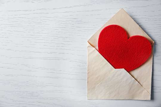 Blank open envelope with heart on wooden background