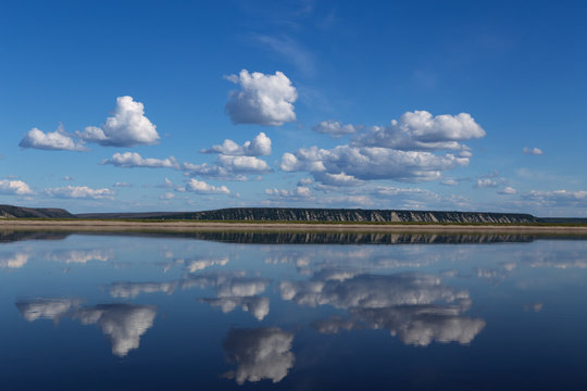 Reflection of clouds in the river and the distant shore. Lena river. Yakutia. Russia.