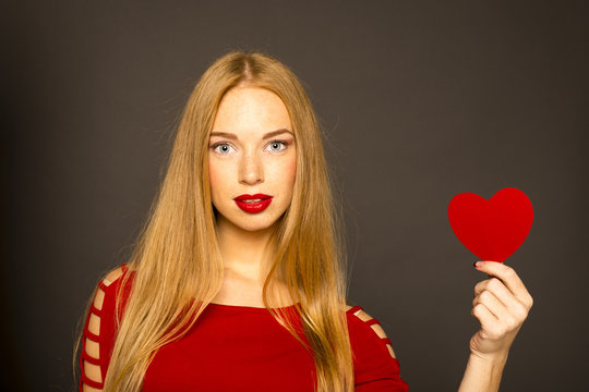 red-haired woman holding a red heart in her hand