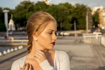 Beautiful blonde young woman wearing fashionable clothes, white cardigan walking on the street . Fashion photo