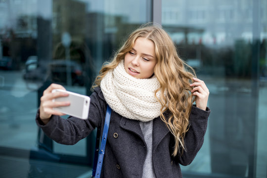 curly blond woman with mobile phone in hand