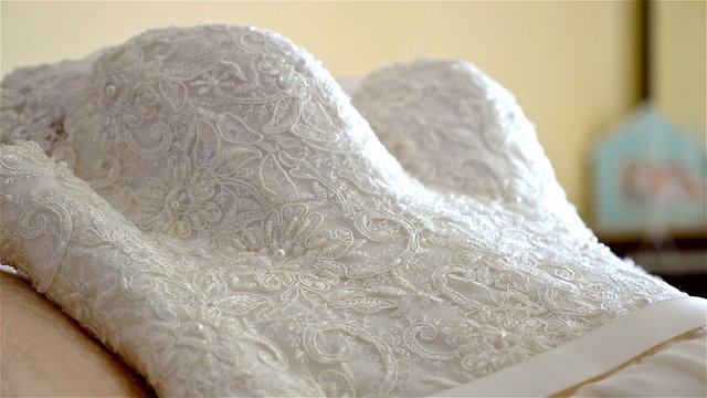 Bride's dress lying on a bed