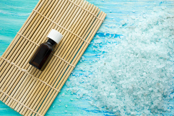  bottles essential oil and sea salt on a blue wooden table, Spa with flowers