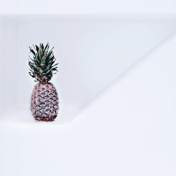 Pineapple in pink paint in white interior. Minimalism fashion