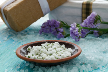 Obraz na płótnie Canvas sea salt on a blue wooden table, with flowers