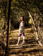 attractive beautiful young woman standing between trees with the sun shining between the break in the trees and shining upon the lady with the trees making a natural border