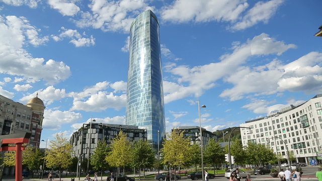 Active urban life, blue summer sky reflecting in modern tall glass building