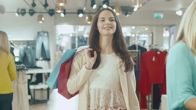 Happy young brunette girl is walking though a clothing store. Shot on RED Cinema Camera.