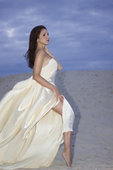 Fototapeta na wymiar Young beauty woman in fluttering beige dress