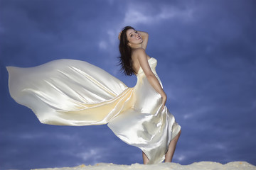 Young beauty woman in fluttering beige dress