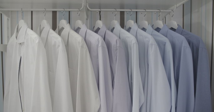 Clean ironed men's shirts set in colors hanging on hangers in the wardrobe flat color
