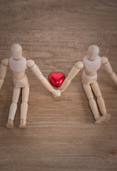 A couple of wooden doll man on valentine days showing love to each other and focus either on heart-shaped chocolate and the couple