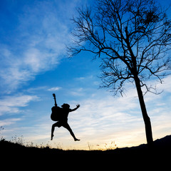 Silhouette boy holding a guitar and jumping