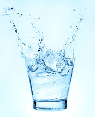 Fototapeta na wymiar Splashing of water with ice in glass on white background.