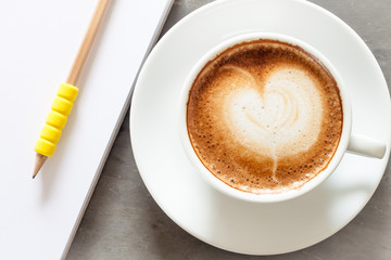 Coffee cup with notepad on grey background