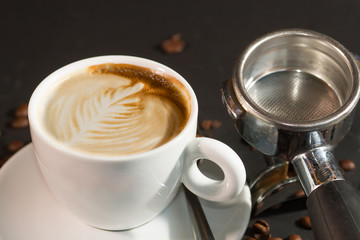 cup of coffee and coffee beans over dark background