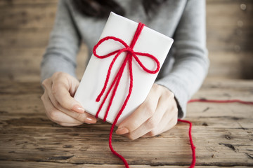 Woman has a gift box of red ribbon