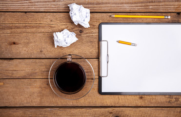 Crumpled paper balls with pencil and clipboard on wooden background, cup of coffee, a wrong idea, business concept