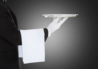 Waiter Holding Empty Silver Tray Over Gray Background