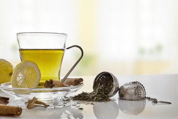 Green tea with cinnamonnd lemon and metallic strainer front view