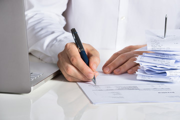 Businessman Analyzing Invoice By Laptop