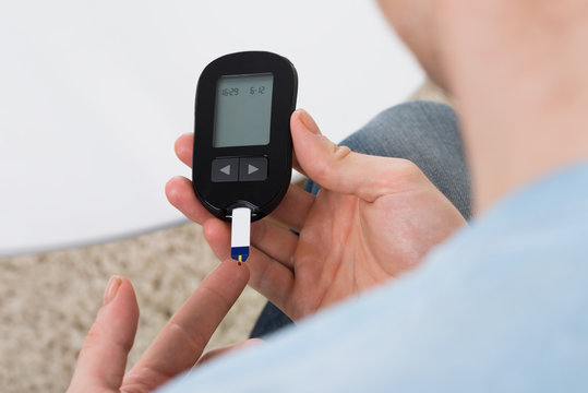 Man Checking Blood Sugar With Glucose Meter