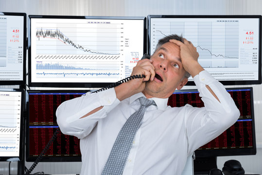 Sad Stock Trader With Hand On Head Using Telephone