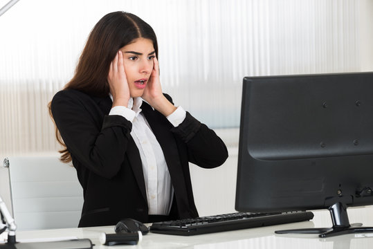 Shocked Businesswoman Looking At Computer Monitor At Desk