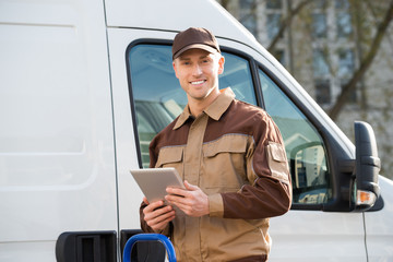 Smiling Delivery Man Holding Digital Tablet Against Truck