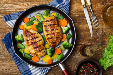 Grilled chicken breast with vegetables in a pan.