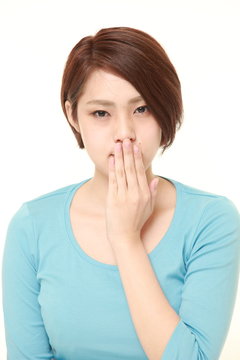 young Japanese woman making the speak no evil gesture