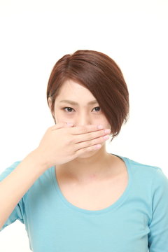 young Japanese woman making the speak no evil gesture