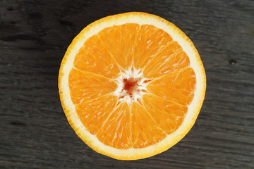 half of ripe orange on wooden table