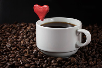 A cup of coffee with a heart on the background of coffee beans