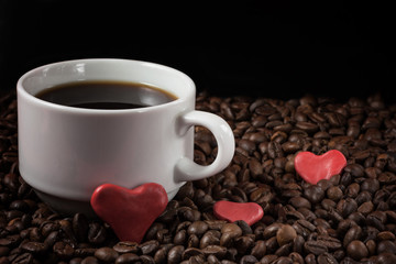 A cup of coffee with a heart on the background of coffee beans