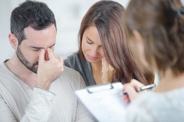 Distressed couple with woman holding clipboard