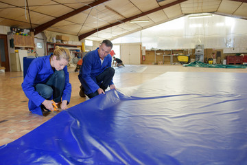 Worker cutting material layed out on floor