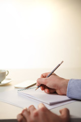 The male hands with a pencil and the cup