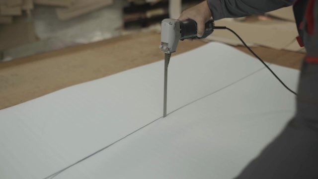 Man cut prepared paralon on encircled line by production knife on factory.