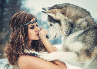 Friendship/ Delightful girl plays with a Siberian Husky in snowy woods © vitx