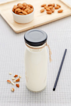 Almond milk in bottle with almonds on table