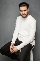 Fototapeta premium sexy fashion man model in white sweater, jeans and boots posing dramatic
