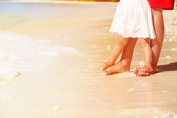 Close up of father and little daughter feet on beach