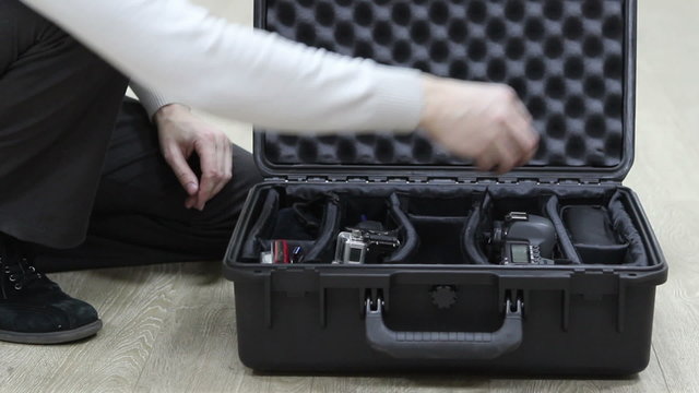 Photographer taking in black safety case photo equipment