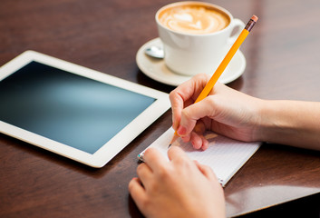 close up of woman writing to notebook with pencil