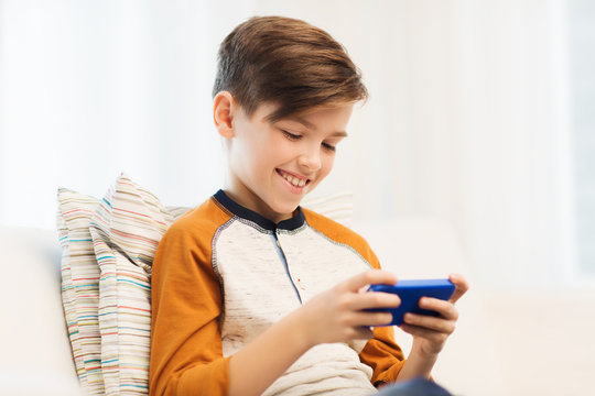 boy with smartphone texting or playing at home