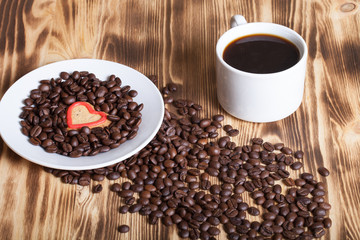 Coffee beans and coffee in white cup on wooden table for backgro