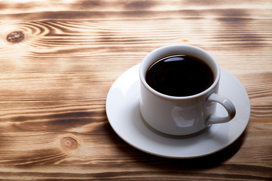 Coffee in cup on light wooden table