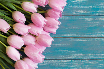 bouquet of pink tulips lie on texture painted in blue color table